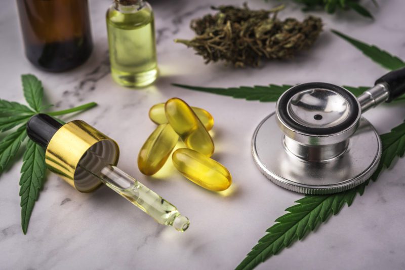 Assorted cannabis products, pills and cbd oil over medical prescription sheet - medical marijuana concept.